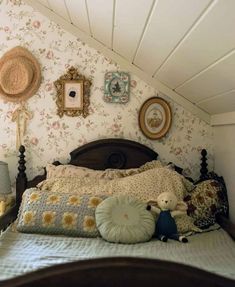 there is a bed with many pillows and pictures on the wall above it in this bedroom