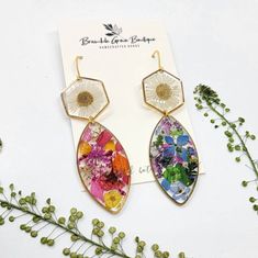 the earrings are decorated with colorful flowers and dangles on top of a white card