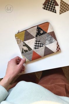 someone is making a patchwork wallet out of fabric