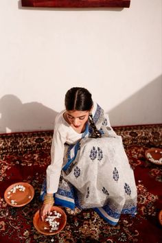 a woman sitting on the floor in front of a bowl filled with white rice and looking at it