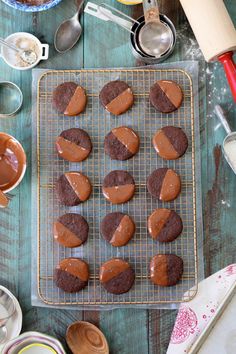 cookies with chocolate frosting on a cooling rack next to other baking supplies and utensils