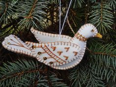 a ceramic bird ornament hanging from a pine tree