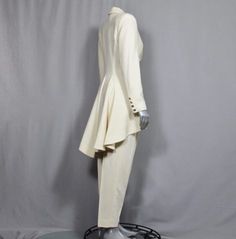 a mannequin dressed in a white suit and hat on a black base stand