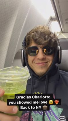 a man wearing headphones and holding a drink