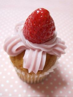 a cupcake with pink icing and a strawberry on top