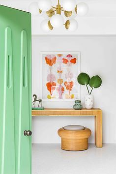 a green door in a white room next to a wooden table with a plant on it