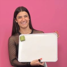 a woman holding a laptop computer in front of a pink wall with polka dots on it