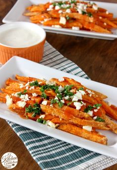 sweet potato fries with feta cheese and parsley on the side in white serving dishes