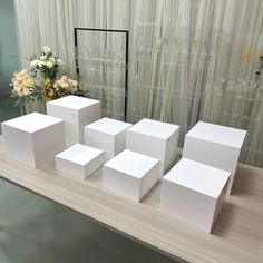 several white boxes sitting on top of a table next to a vase filled with flowers