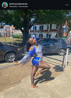 a woman in a blue and white costume is dancing on the sidewalk next to a parking meter