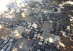 the sidewalk is made out of cobblestones and there are trees in the background