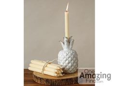 a pineapple shaped candle holder on a wooden table with some candles in front of it