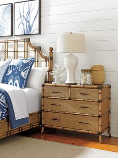 a bed with blue and white pillows on top of it next to a dresser in a bedroom