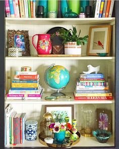 a bookshelf filled with lots of books and vases on top of it