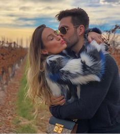 a man and woman kissing in front of a vineyard