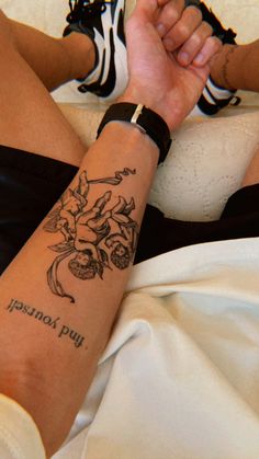 a woman with a tattoo on her arm sitting in bed next to a white pillow