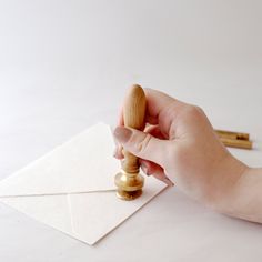 a hand holding a rubber stamp on top of a piece of paper next to a envelope