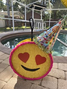 a smiley face pinata sitting on top of a table next to a pool