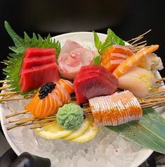 a plate with different types of sushi on skewers and garnishes