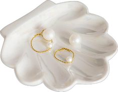 a pair of gold - plated and pearl earrings on a white flower shaped dish