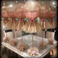 some pink and gold balloons are sitting on a table with tulle skirted chairs