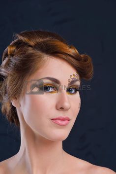 a woman with makeup on her face and gold eyeshadow is posing for the camera