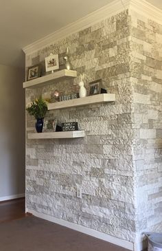 a stone wall with shelves and vases on the top, in a living room