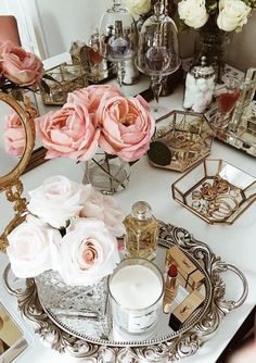 a white table topped with lots of flowers and candles on top of a metal tray