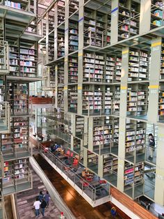 the interior of a large library filled with lots of books and people walking through it