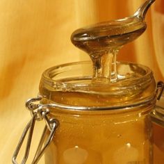 a glass jar filled with liquid sitting on top of a wooden table next to a spoon