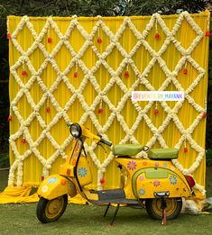 a yellow scooter parked in front of a decorative wall