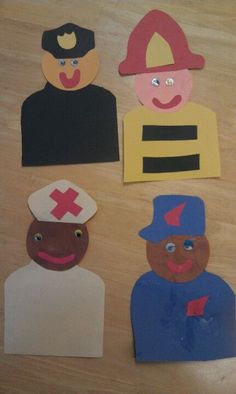 paper cut out of different people on a wooden table with one person wearing a fireman's hat