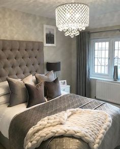 a bedroom with a large bed and a chandelier hanging from it's ceiling