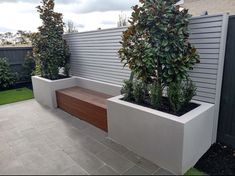 two large planters with plants in them on the side of a house's patio