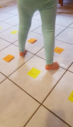 a woman standing on top of a tiled floor next to yellow post - it notes