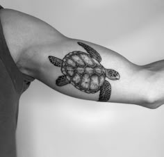 a black and white photo of a man's arm with a turtle tattoo on it