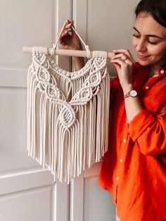 a woman is holding up a white macrame