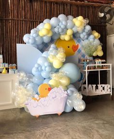 balloons and rubber ducks decorate the backdrop for a baby's bathtub themed birthday party