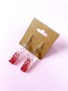 - Handmade Resin Jewelry -  The Rectangle Red Confetti Earrings are perfect for night out! Earrings in the shop are one-of-a-kind creations using resin, findings, and various natural and manmade materials. They are fun, lightweight, and comfortable to wear on all occasions. Due to the pieces being handmade with various materials, there may be small imperfections such as bubbles or markings. Please refer to the FAQs section of the shop to learn more about caring for your resin jewelry.  Please re Red Confetti, Diy Resin Projects, Rectangle Earrings, Jewelry Care Instructions, Custom Tags, Jewelry Card, Etsy Earrings Dangle, Resin Diy, Resin Jewelry