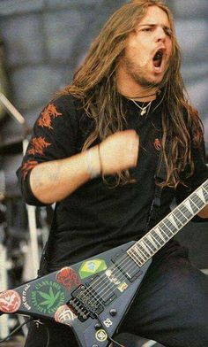 a man with long hair playing an electric guitar