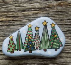 a painted rock with christmas trees on it