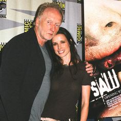 two people standing next to each other in front of a movie poster at an event