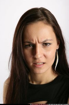 a woman with long brown hair and large hoop earrings on her face is looking at the camera