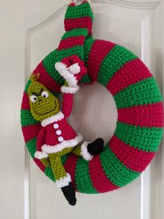 a crocheted christmas wreath hanging on the front door with an elf's hat