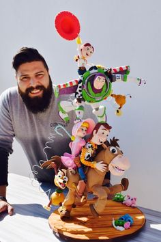 a man standing next to a wooden sculpture with toy characters on it's sides