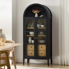 a black cabinet with glass doors and drawers in a living room area next to a dining table