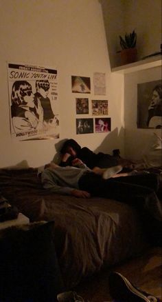 a person laying on a bed in a room with posters hanging on the wall behind them