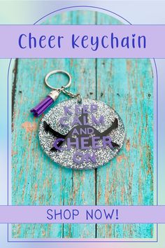 a keychain with the words keep calm and cheer on it in purple lettering