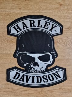 the harley davidson logo is shown in black and white on a wooden surface with a skull