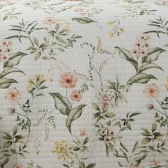 a white quilt with flowers and leaves on it